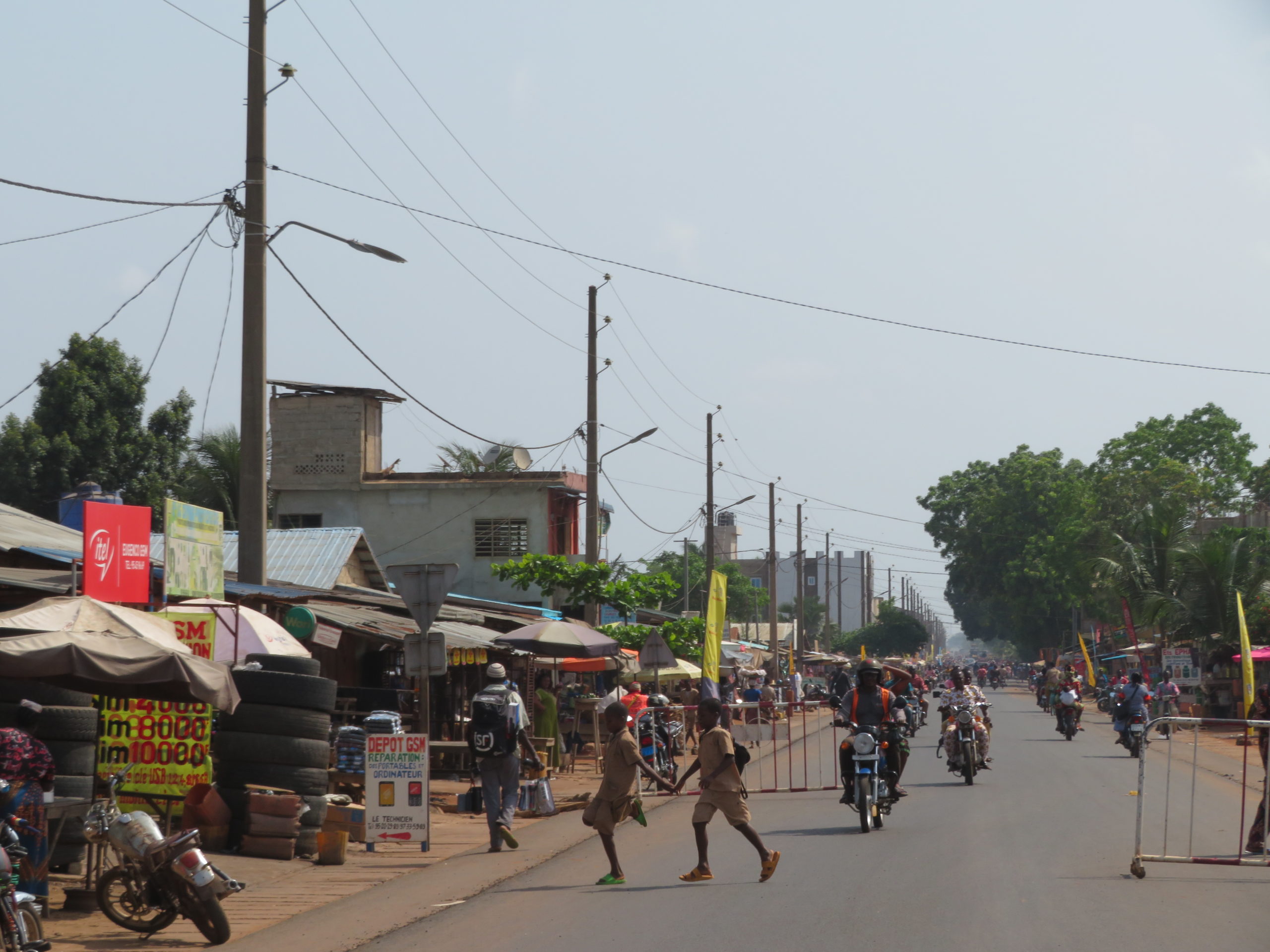 Town and street in Benin with vehicles and shops