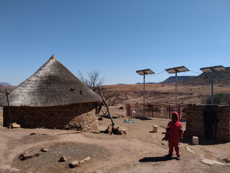Child in desert with house and solar panel