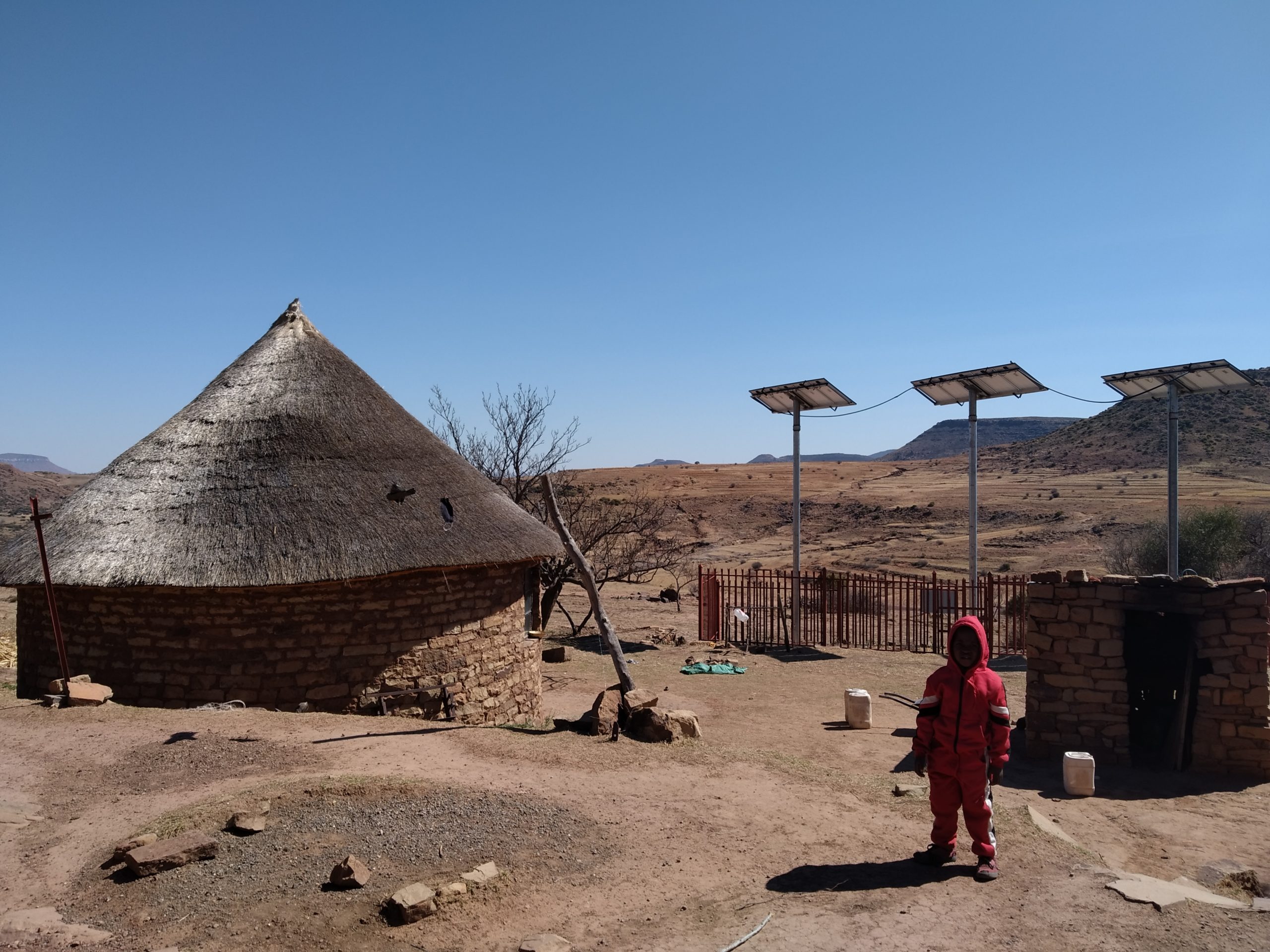 Child in desert with house and solar panel