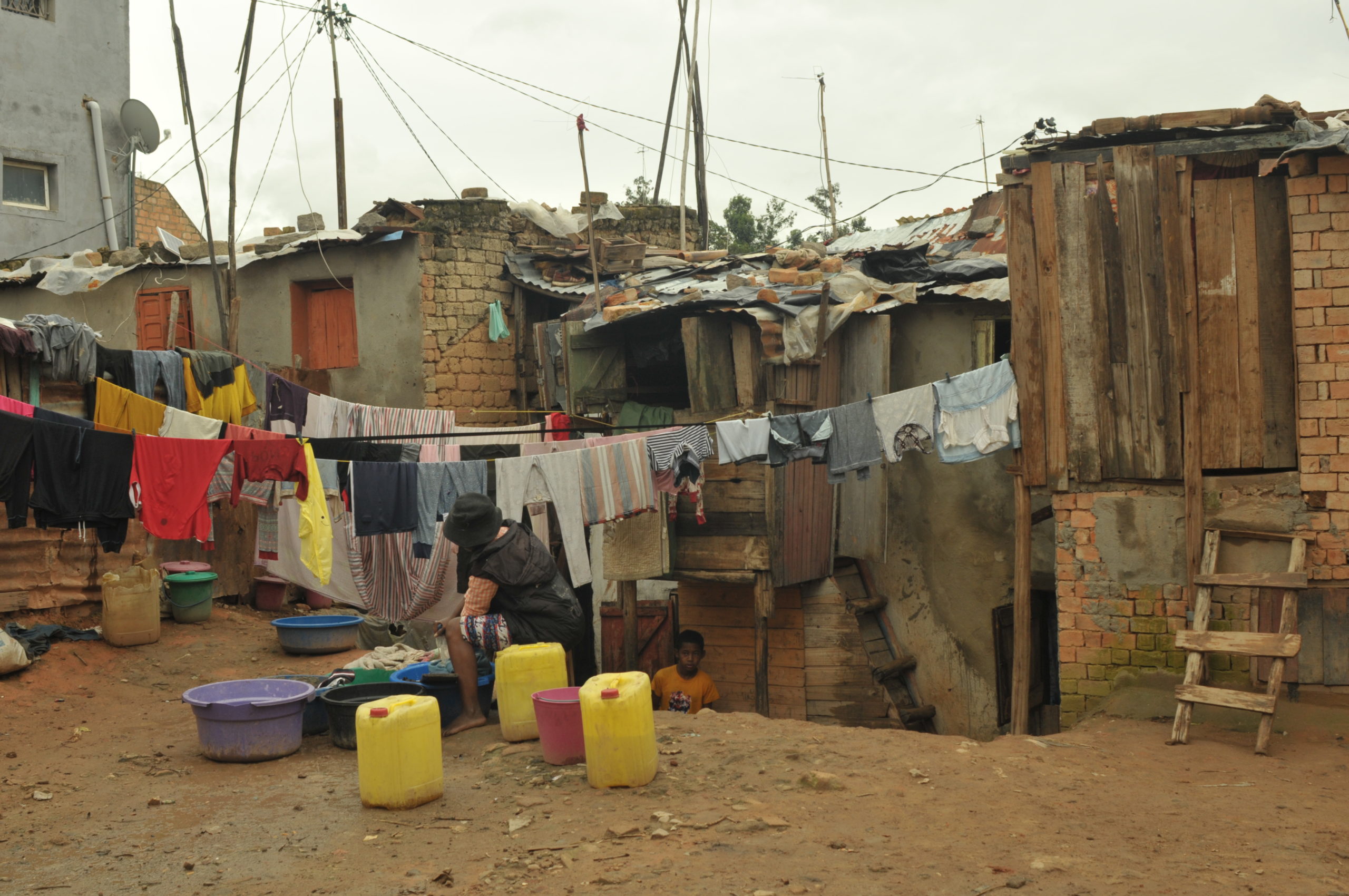 A person washing clothes using jerry cans outside their house in Antananarivo